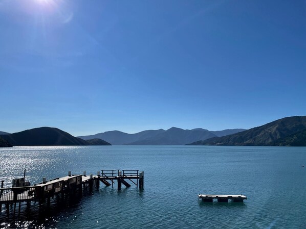 A calm lake with a wooden pier extending into the water, surrounded by mountains.