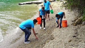 A group of people by a riverbank, some holding buckets, possibly collecting water or debris. - The Lodge At Te Rawa - Boat Access Only (Te Rawa)