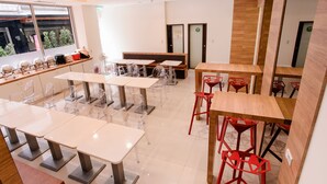 A modern dining area with multiple tables and chairs, a wooden bench, and a view of the outdoors through a large window. - Kiwi Express Hotel - Taichung Station Branch 10 (Taichung)