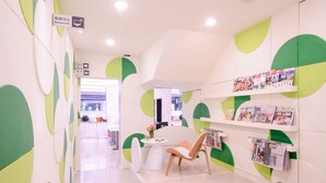 A modern interior with a reception desk, a chair, and a wall with circular patterns. - Kiwi Express Hotel - Taichung Station Branch 10 (Taichung)