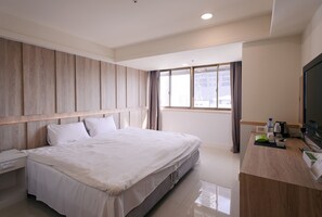 A hotel room with a large bed, a wooden headboard, a desk with a television, and a window with curtains. - Kiwi Express Hotel - Taichung Station Branch 10 (Taichung)