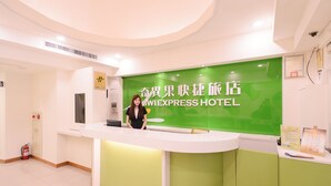 A reception desk with a green backdrop and a sign reading "WEXPRESS HOTEL". - Kiwi Express Hotel - Taichung Station Branch 10 (Taichung)