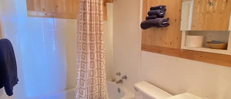 Bañera con ducha, toallas, jabón, shampoo