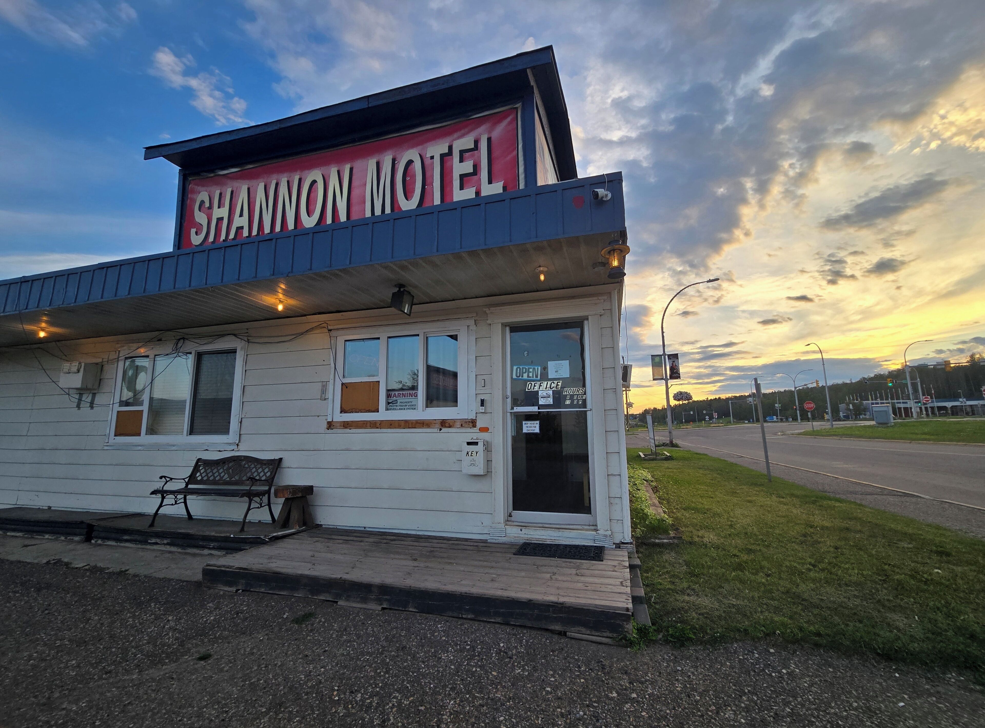 Un motel pequeño con un letrero que dice 'SHANNON MOTEL' y una banca en el exterior.