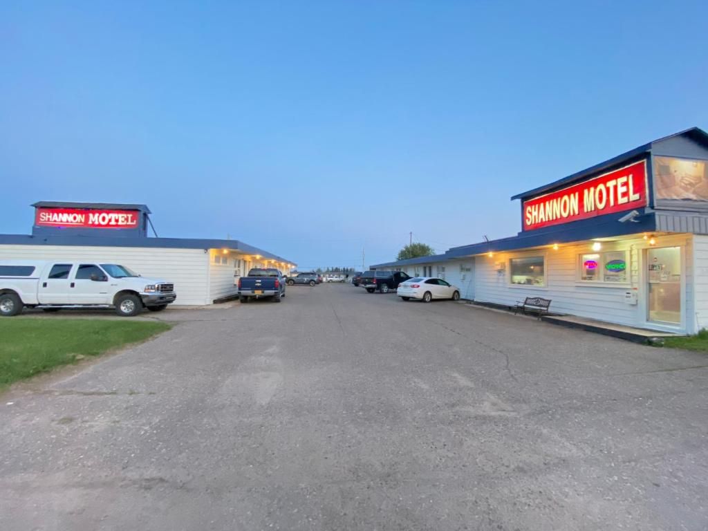 Un motel con un letrero que dice 'SHANNON MOTEL' y un estacionamiento con varios vehículos.