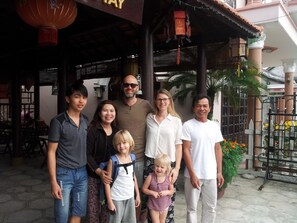 A group of people standing in front of a building with a traditional architectural style, featuring a tiled roof and wooden beams. - Homeland River Homestay (Da Nang)