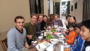 Un grupo de personas sentadas alrededor de una mesa con diferentes platos, sugiriendo un ambiente de comida compartida.