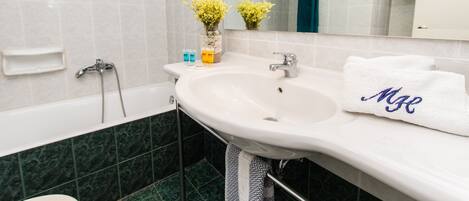 Une salle de bain avec un lavabo blanc, un miroir et une serviette ornée de monogrammes.