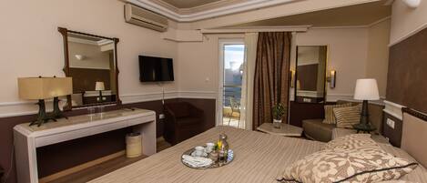 Habitación de hotel con cama, escritorio, silla, televisor y vistas al balcón.