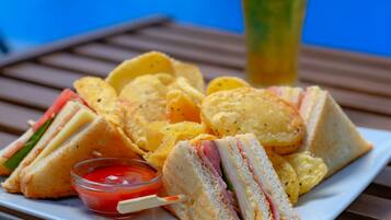 A plate of sandwiches, chips, and a drink by a pool.