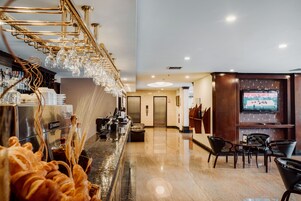 Un vestíbulo de hotel con área de bar, asientos y una pantalla de televisión.