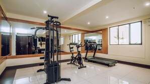 Een moderne sportschool met diverse fitnessapparaten, waaronder een loopband, een hometrainer en krachttoestellen.