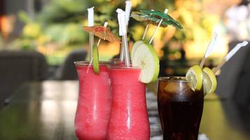 Three drinks on a table with a blurred outdoor background.