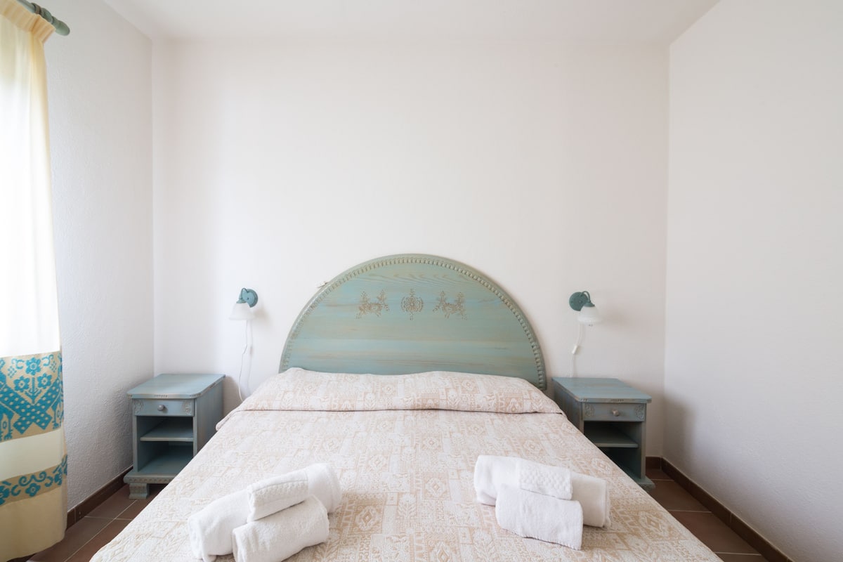 A bedroom with a bed, two bedside tables, and a nightstand.