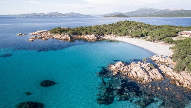 A coastal landscape with clear blue waters, rocky shores, and a sandy beach. - Residence Costa Ruja (Olbia)