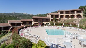 A resort with a swimming pool, outdoor seating, and a mountainous backdrop. - Residence Costa Ruja (Olbia)