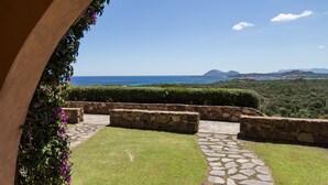 A stone pathway leading to a seating area with a view of the ocean and distant mountains. - Residence Costa Ruja (Olbia)
