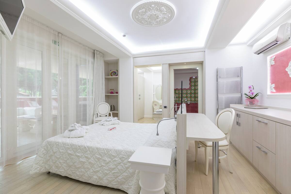 A modern hotel room with a bed, a desk, and a bathroom.