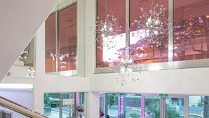 A spacious, multi-level interior with a staircase, seating areas, and large windows offering views of the outdoors. - Paradiso Hotel Bovelacci (Cervia)