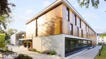 A modern building with a flat roof, large windows, and a paved entrance area with a bicycle rack.