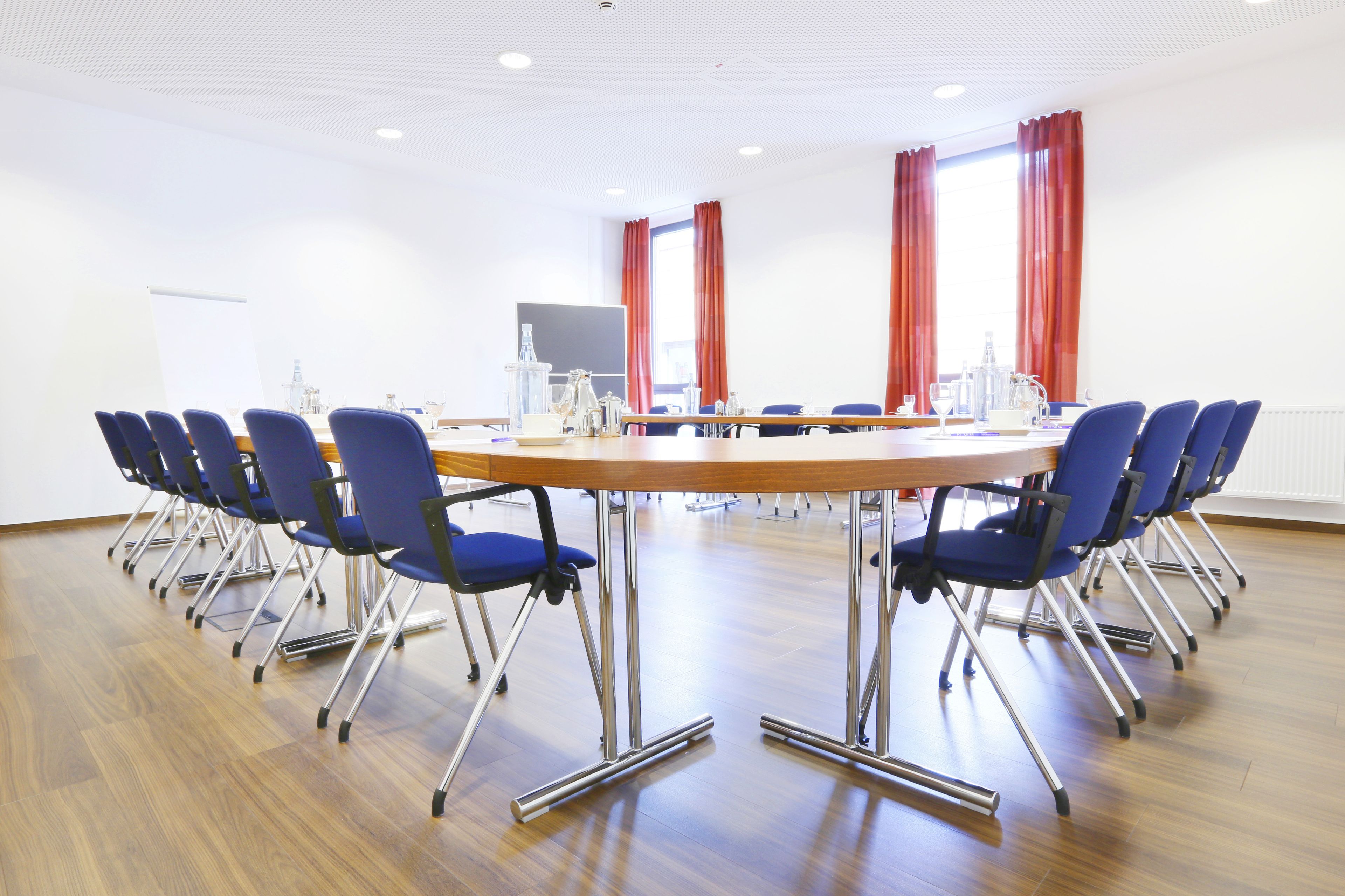 A conference room with a long table, blue chairs, and a whiteboard.
