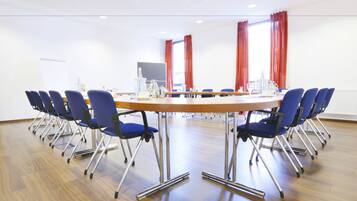 A conference room with a long table, blue chairs, and a whiteboard.