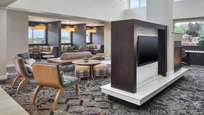 Eine geräumige Lobby mit einem großen Flachbildfernseher, bequemen Sitzgelegenheiten und Blick ins Freie.