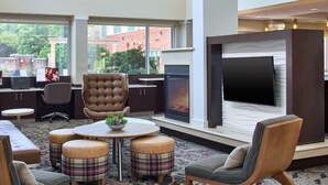 Ein moderner Lounge-Bereich mit Kamin, bequemen Sitzgelegenheiten und einem großen Flachbildfernseher.
