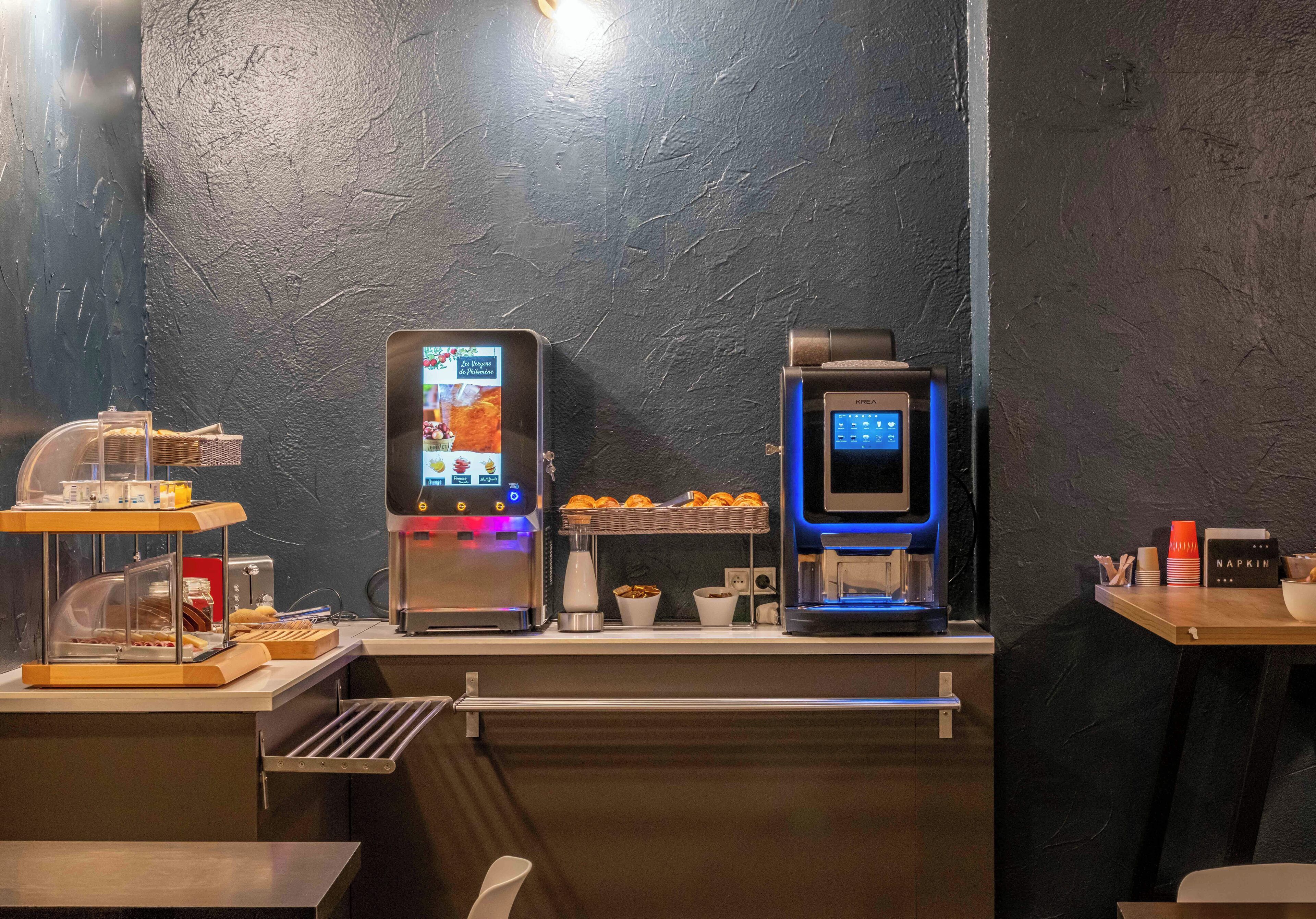 Ein Selbstbedienungs-Frühstücksbereich mit einer Kaffeemaschine, einem digitalen Menü und einer Brodauslage.