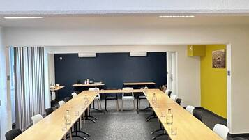 Un salón de conferencias con una larga mesa, sillas y una pantalla para proyector.