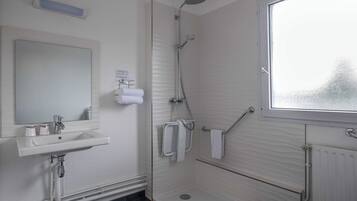 Un baño con lavamanos, espejo, ducha y ventana.