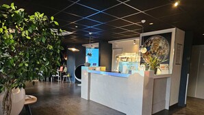 A modern reception area with a reception desk, a large potted plant, and a wall-mounted globe. - The originals Hotel Ariane, Toulouse (Toulouse)