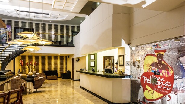 A hotel lobby with a reception desk, seating area, and a staircase. - Hotel Ciudad Bonita (Bucaramanga)