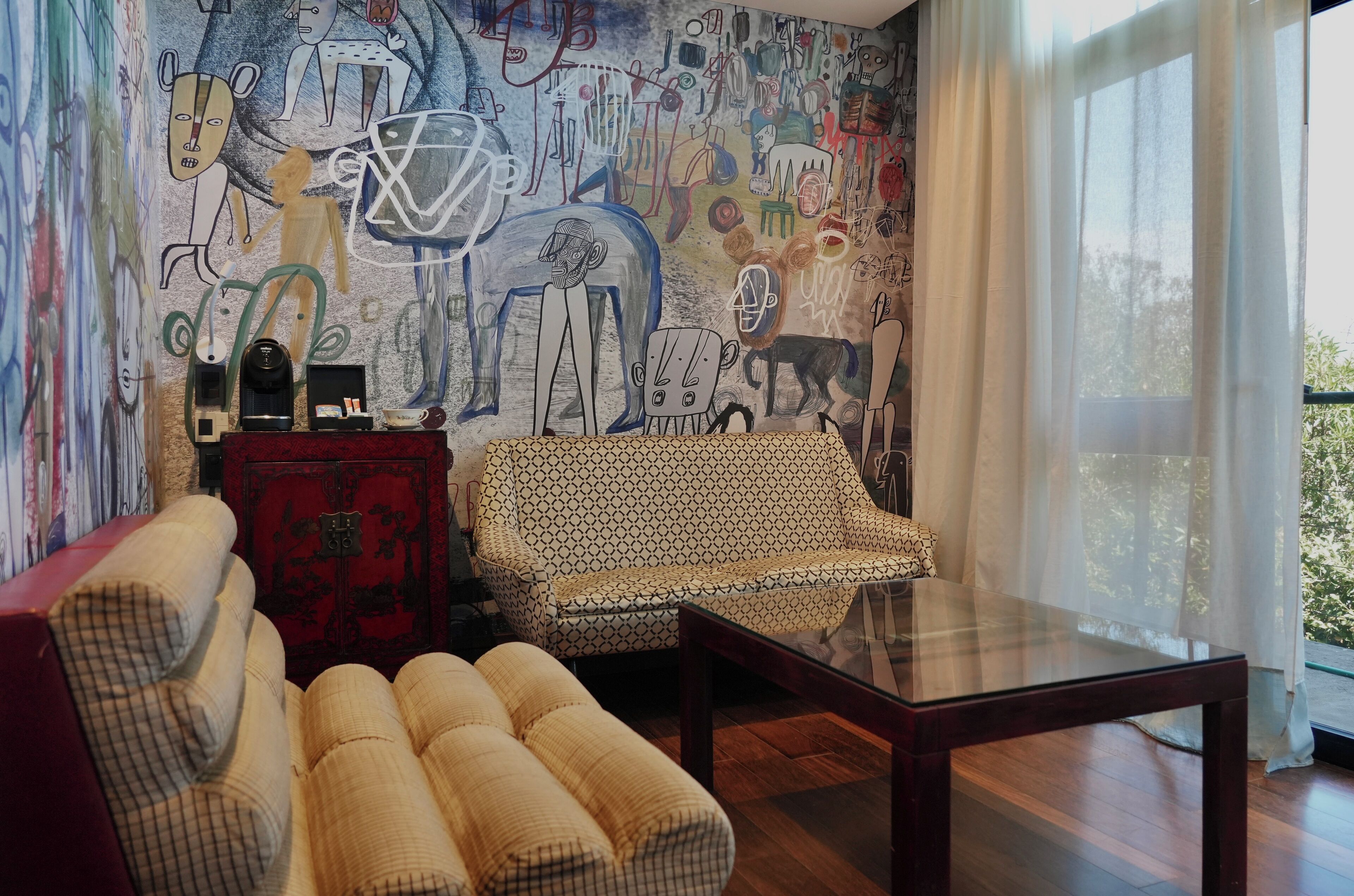 A living room with a patterned sofa, a red cabinet, and a glass coffee table.