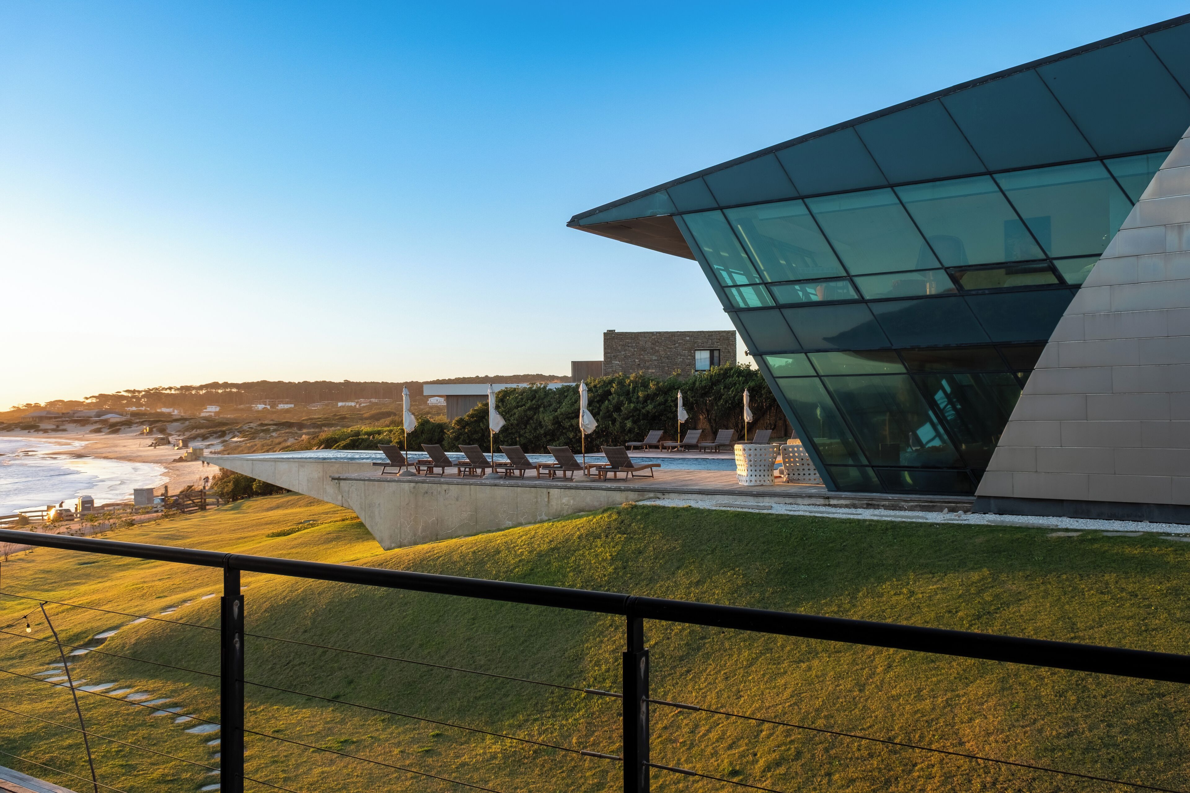 A modern building with a glass facade overlooking a beach.