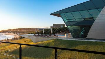 A modern building with a glass facade overlooking a beach.