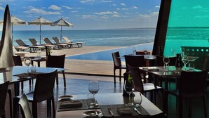 A dining area with a view of the ocean, featuring tables, chairs, and umbrellas. - Playa Vik Jose Ignacio (José Ignacio)