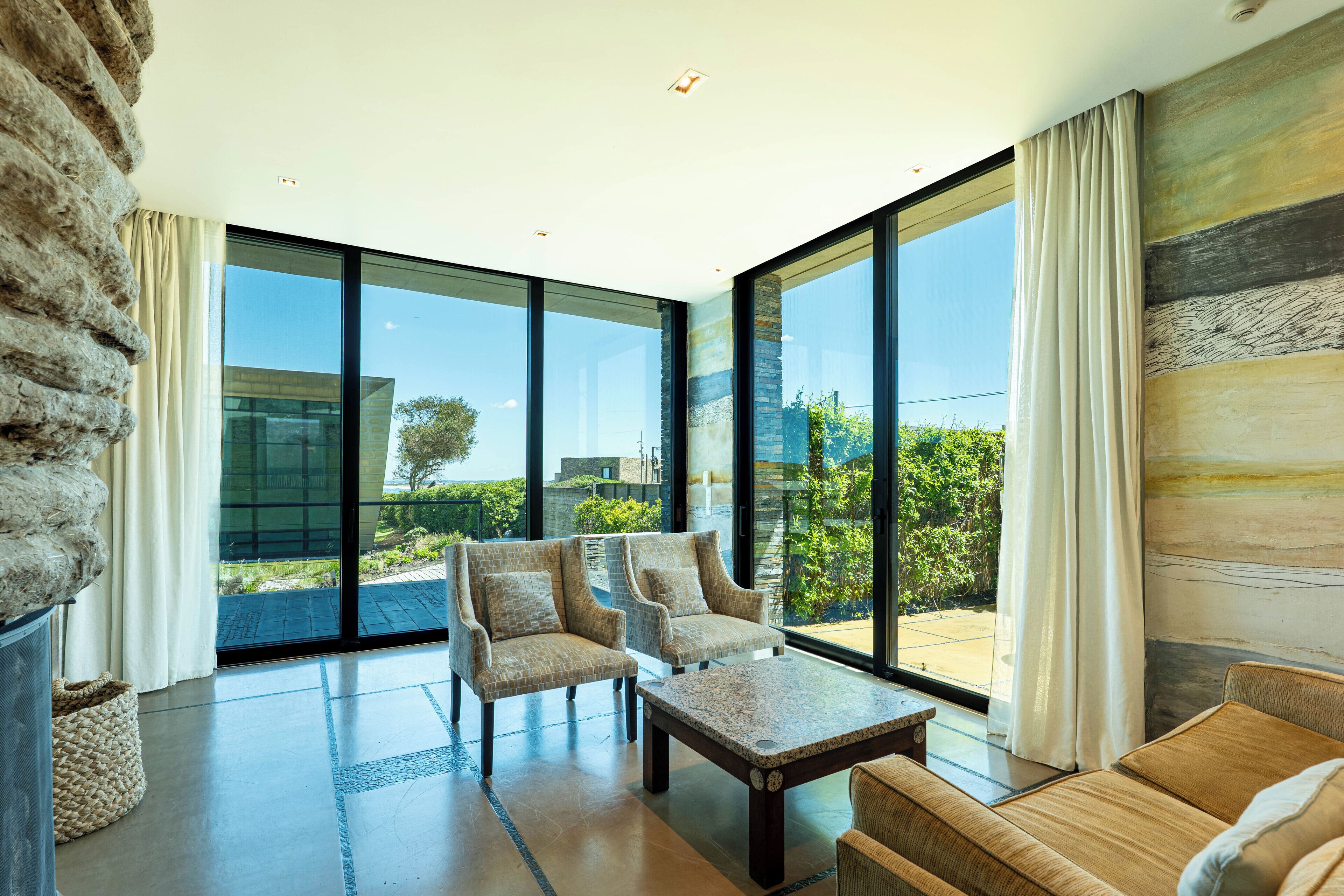 A spacious living room with large windows, a stone wall, and a view of the outdoors.