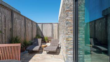 A patio with stone flooring, wicker furniture, and potted plants.
