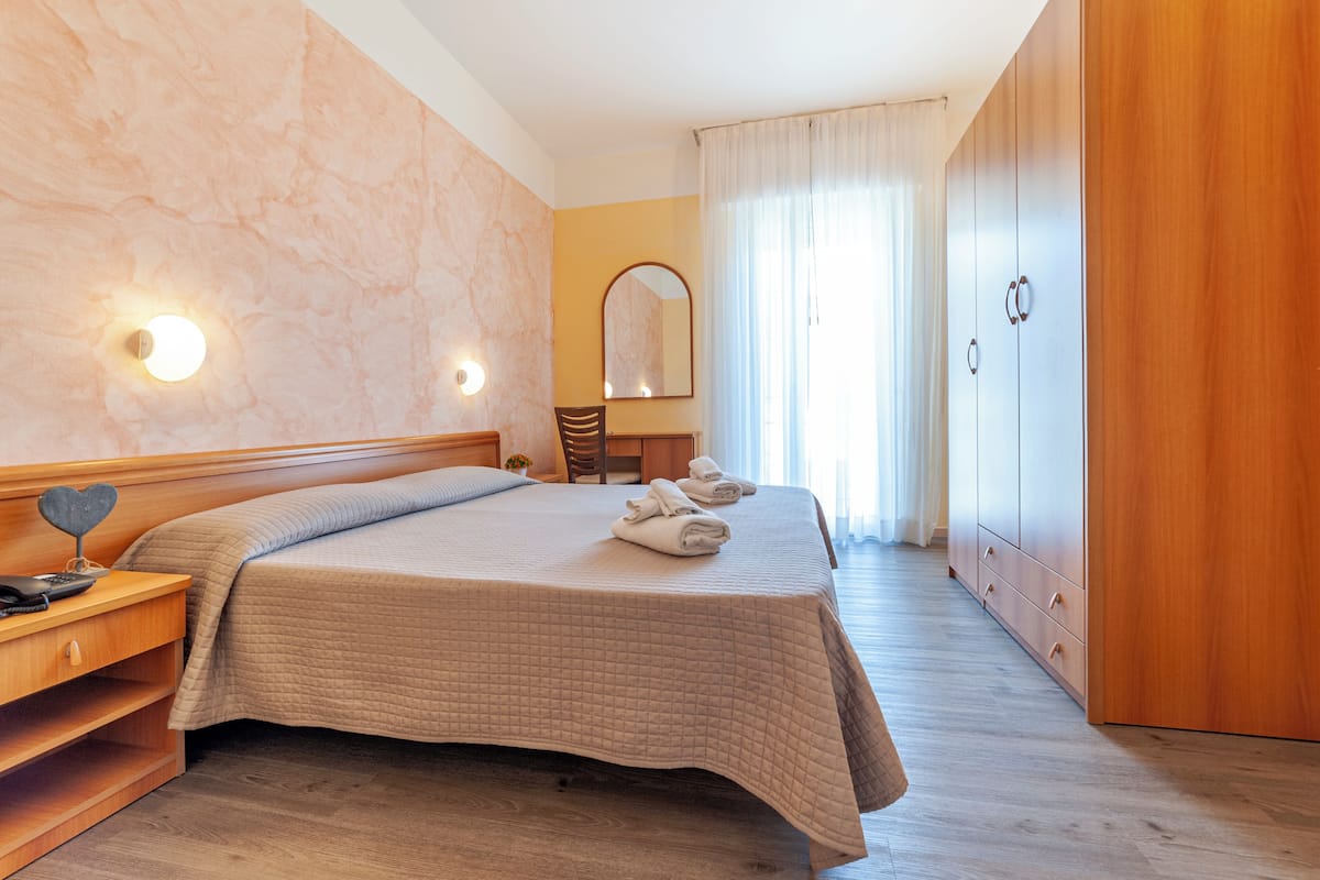Ein ordentlich eingerichtetes Schlafzimmer mit Bett, Nachttisch und Kleiderschrank.