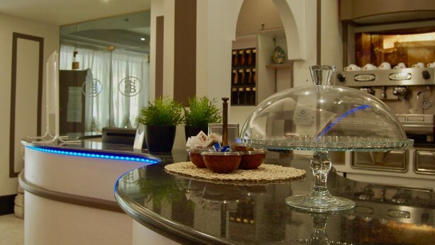 Une cuisine moderne dotée d’un îlot central avec un plan de travail en verre, d’une machine à café et d’un bol décoratif.