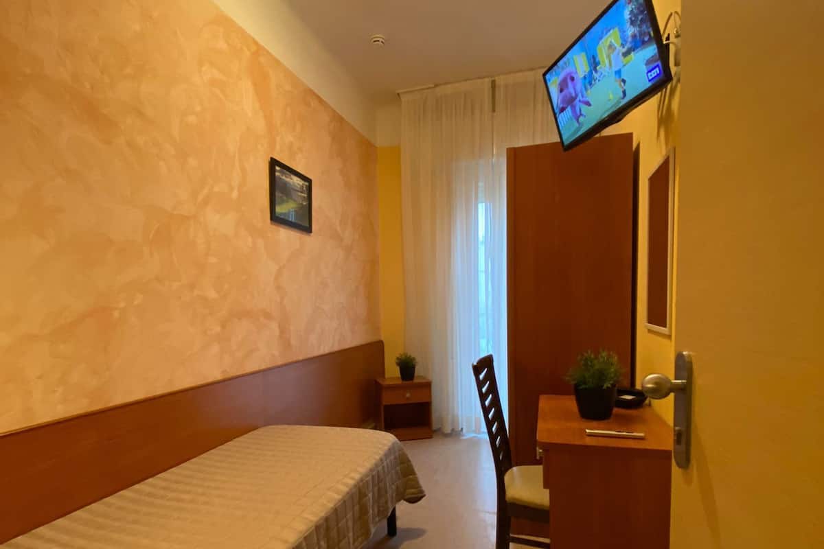 Ein Hotelzimmer mit Bett, Schreibtisch mit Stuhl, Fernseher und Tür.