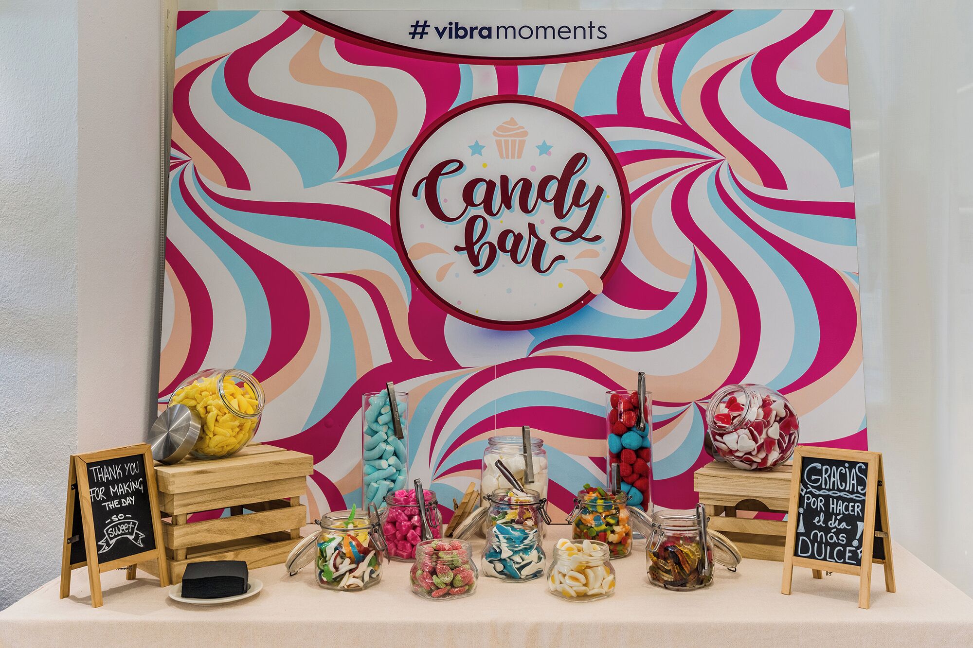 Una exhibición de barras de caramelo con frascos de dulces variados y un cartel que dice 'Candy bar'.