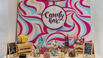 Una exhibición de barras de caramelo con frascos de dulces variados y un cartel que dice 'Candy bar'.