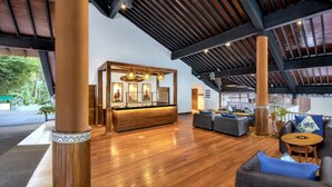 Un hall d’entrée spacieux, doté d’un comptoir de réception en bois, de sièges confortables et d’un plafond haut avec des poutres apparentes.