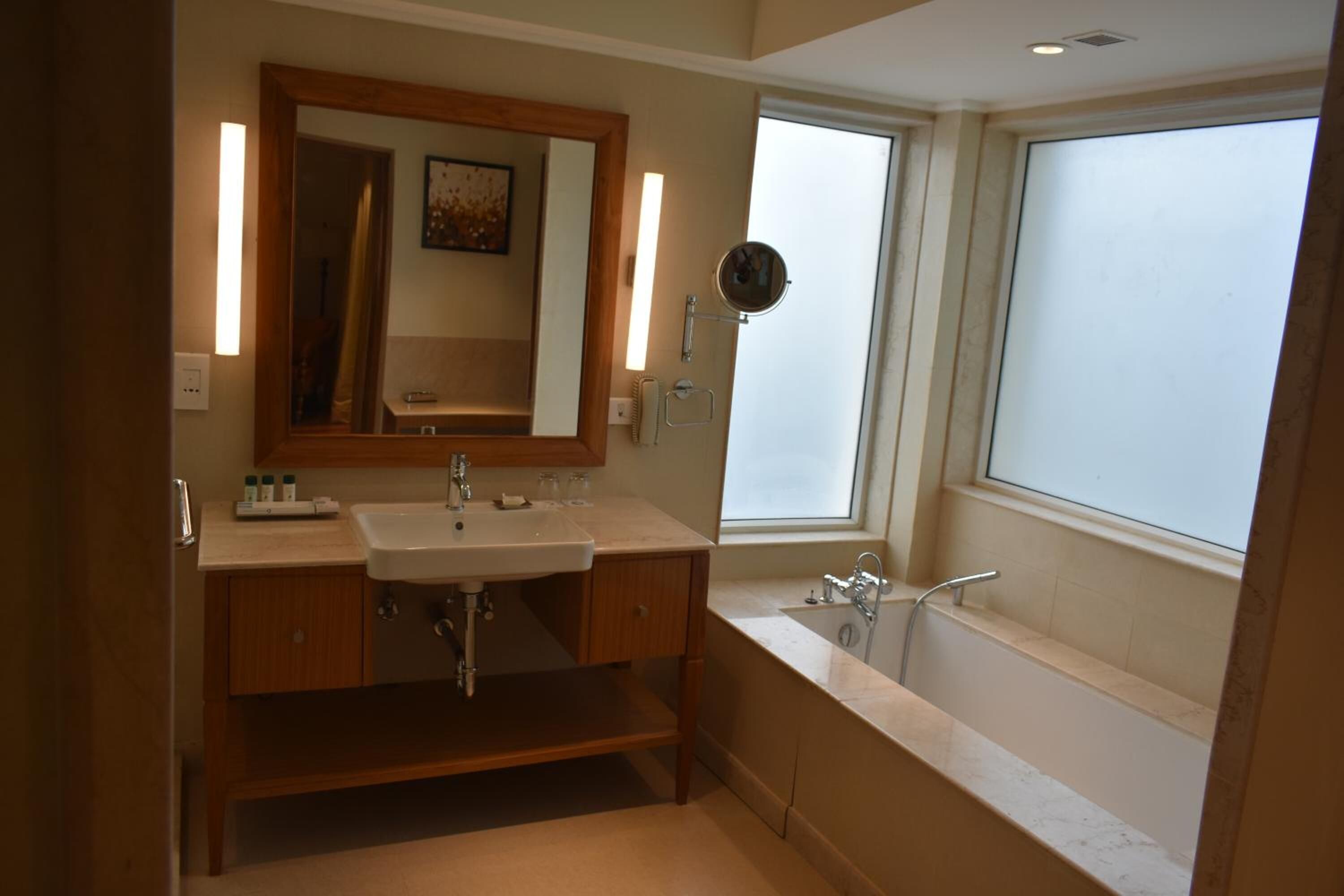 Een badkamer met een wastafel, spiegel, wastafelmeubel en bad.