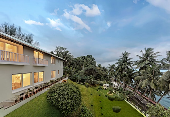 A modern building with multiple balconies, a well-maintained lawn, and a view of the ocean.