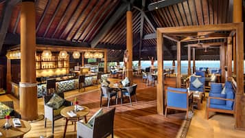 A spacious indoor area with wooden flooring, high ceilings, and a bar area with illuminated shelves.