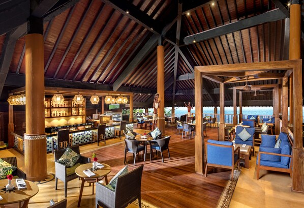 A spacious indoor area with wooden flooring, high ceilings, and a bar area with illuminated shelves.
