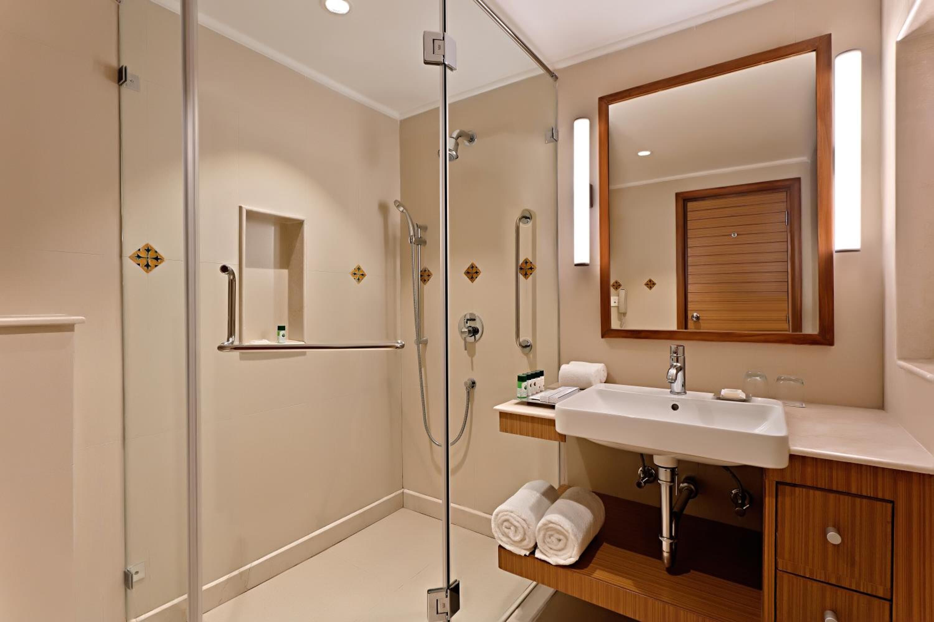 A modern bathroom with a glass-enclosed shower, a vanity with a sink, and a large mirror.